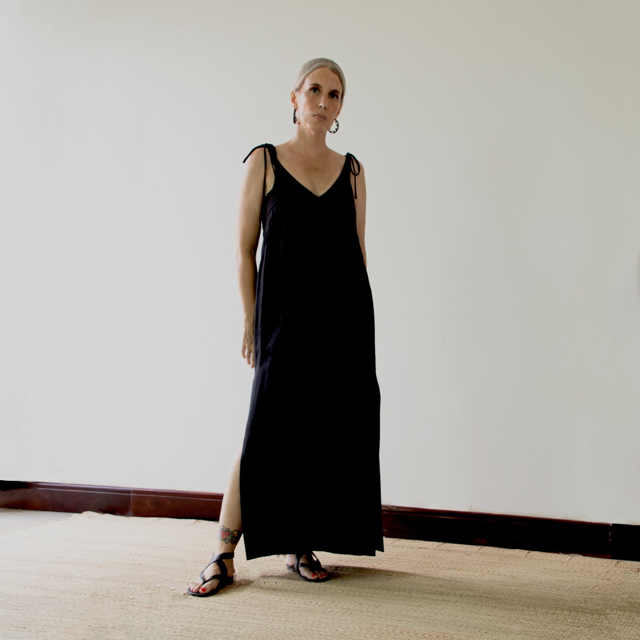 Woman wearing the Teia Dress sewing pattern from Pattern Fantastique on The Fold Line. A shift dress pattern made in linen, silk, rayon or tencel fabrics, featuring a loose fit, maxi length, deep V-neck, adjustable shoulder straps and high side splits.