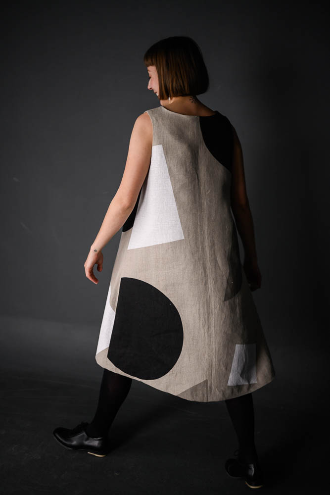 Woman wearing the Trapeze Dress sewing pattern from Merchant & Mills on The Fold Line. A sleeveless dress pattern made in linen, cotton, wool suiting or needlecord fabrics, featuring an A-line silhouette, round neckline, relaxed fit and below knee length
