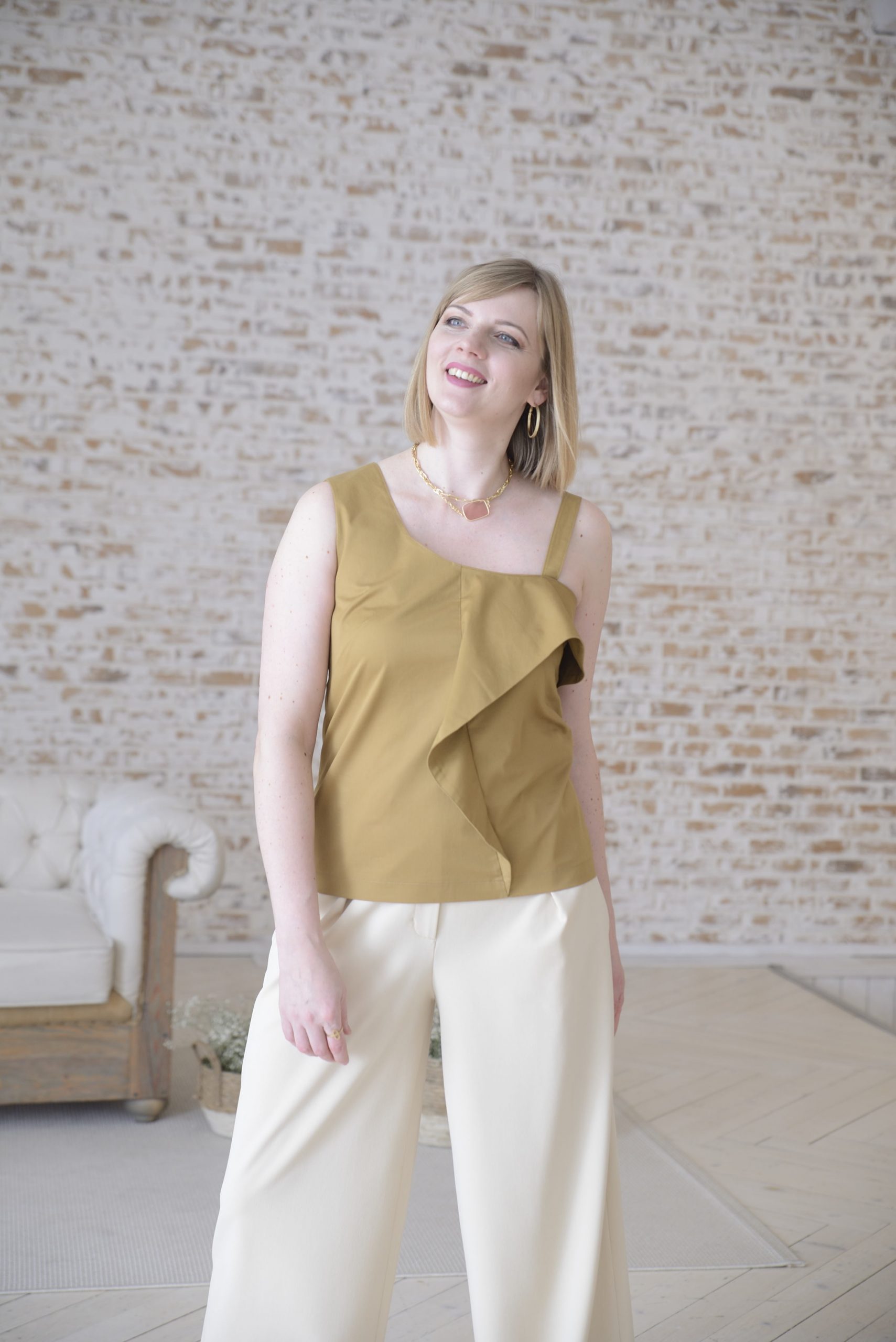 Woman wearing the Ylia Top sewing pattern from Lenaline Patterns on The Fold Line. A top pattern made in cotton, linen, viscose, cotton plumetis, thin wool or denim fabrics, featuring an asymmetrical neckline, front bodice ruffle, one narrow and one broad