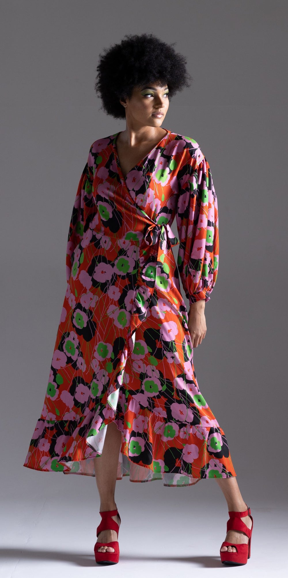 Woman wearing the Darjeeling Frock sewing pattern from Sew Different on The Fold Line. A wrap dress pattern made in viscose, crepe, georgette, tencel and cupro fabrics, featuring a midi length asymmetric frilled tiered hemline, crossover bodice with side