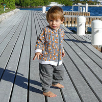 Child wearing the Child/Baby Zip-Up Hoodie sewing pattern from Elemeno Patterns on The Fold Line. A T-shirt pattern made in cotton knit fabrics, featuring long sleeves, cuff and hem bands, hood, front pockets and front zip closure.