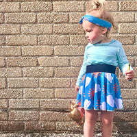 Child wearing the Child/Baby Circle Skirt sewing pattern from Elemeno Patterns on The Fold Line. A circle skirt pattern made in knit fabrics, featuring a broad waist band and above knee finish.