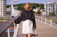 Woman wearing the Antonina Skirt sewing pattern from Lenaline Patterns on The Fold Line. A wrap skirt pattern made in denim, gabardine, jacquard, velvet, suede or tweed fabrics, featuring an A-line silhouette, crossover front with button closure and above