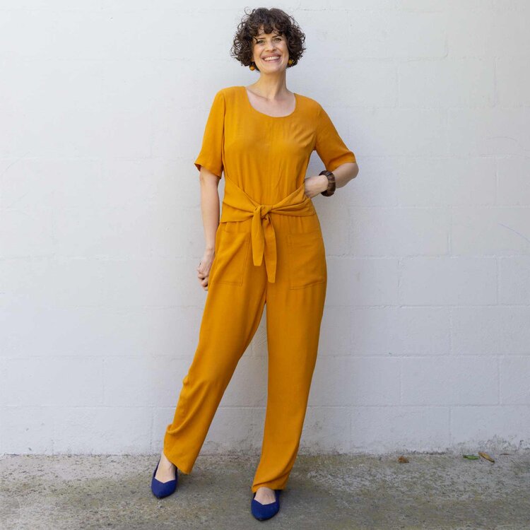 Woman wearing showing the Dana Jumpsuit sewing pattern from Sew DIY on The Fold Line. A jumpsuit pattern made in linen, chambray, cotton lawn, poplin, rayon, tencel or crepe de chine fabrics, featuring a front waist tie that creates subtle shaping, scoop 