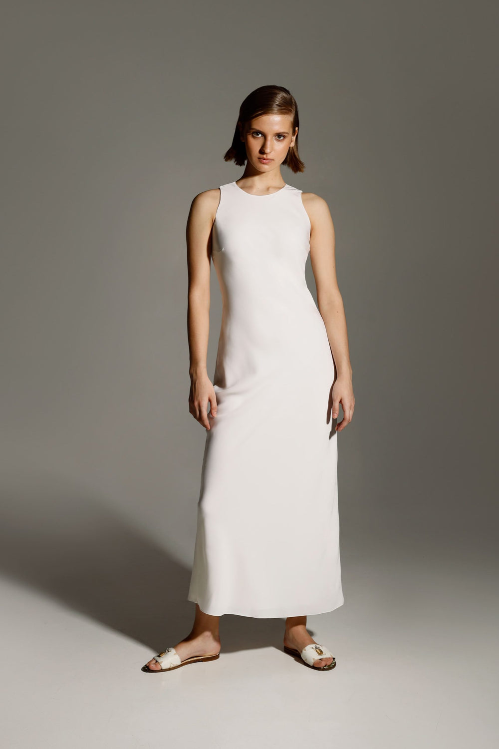 Woman wearing the Ailyn Dress sewing pattern from Vikisews on The Fold Line. A sleeveless dress pattern made in natural silk, faux silk, crepe satin or dress-weight viscose fabrics, featuring a close-fitting silhouette, bias cut, bust darts, button and lo