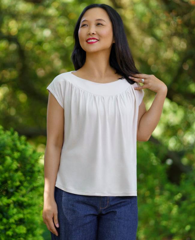Woman wearing the Algarve Top sewing pattern from Itch to Stitch on The Fold Line. A knit top pattern made in rayon/viscose/bamboo jersey, lightweight French terry, double-brushed poly, or ITY fabric, featuring a wide boat neck with front and back yokes, 