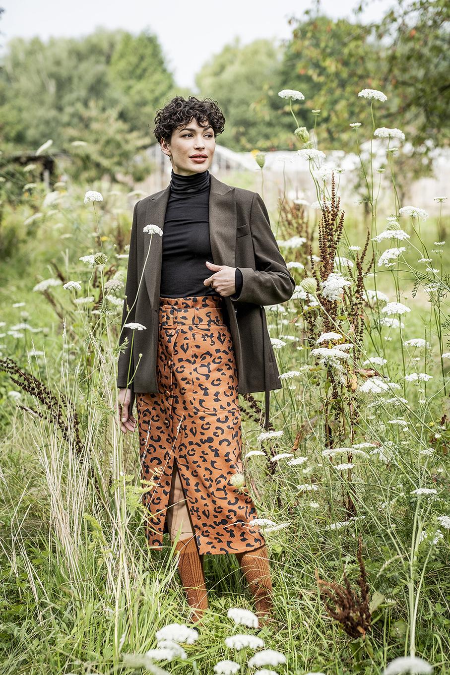 Woman wearing the Alida Skirt sewing pattern from Fibre Mood on The Fold Line. A skirt pattern made in cotton twill, leather, denim, corduroy or velvet fabrics, featuring patch pockets, paper bag waist, front button closure, front slit, fabric covered bel