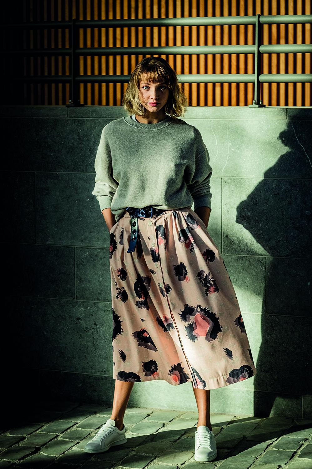 Woman wearing the Alix Skirt sewing pattern from Fibre Mood on The Fold Line. A skirt pattern made in poplin, twill, chambray, corduroy, Tencel, crêpe or satin fabrics, featuring a button front closure, subtle pleating, waistband with belt loops, side sea