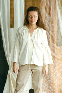 Woman wearing the Amaya Shirt sewing pattern from Made My Wardrobe on The Fold Line. A shirt pattern made in cotton, muslin, silk or linen fabrics, featuring a relaxed fit, raglan shoulders, gathered sleeves, V-neck, gathered neck and neck tie.