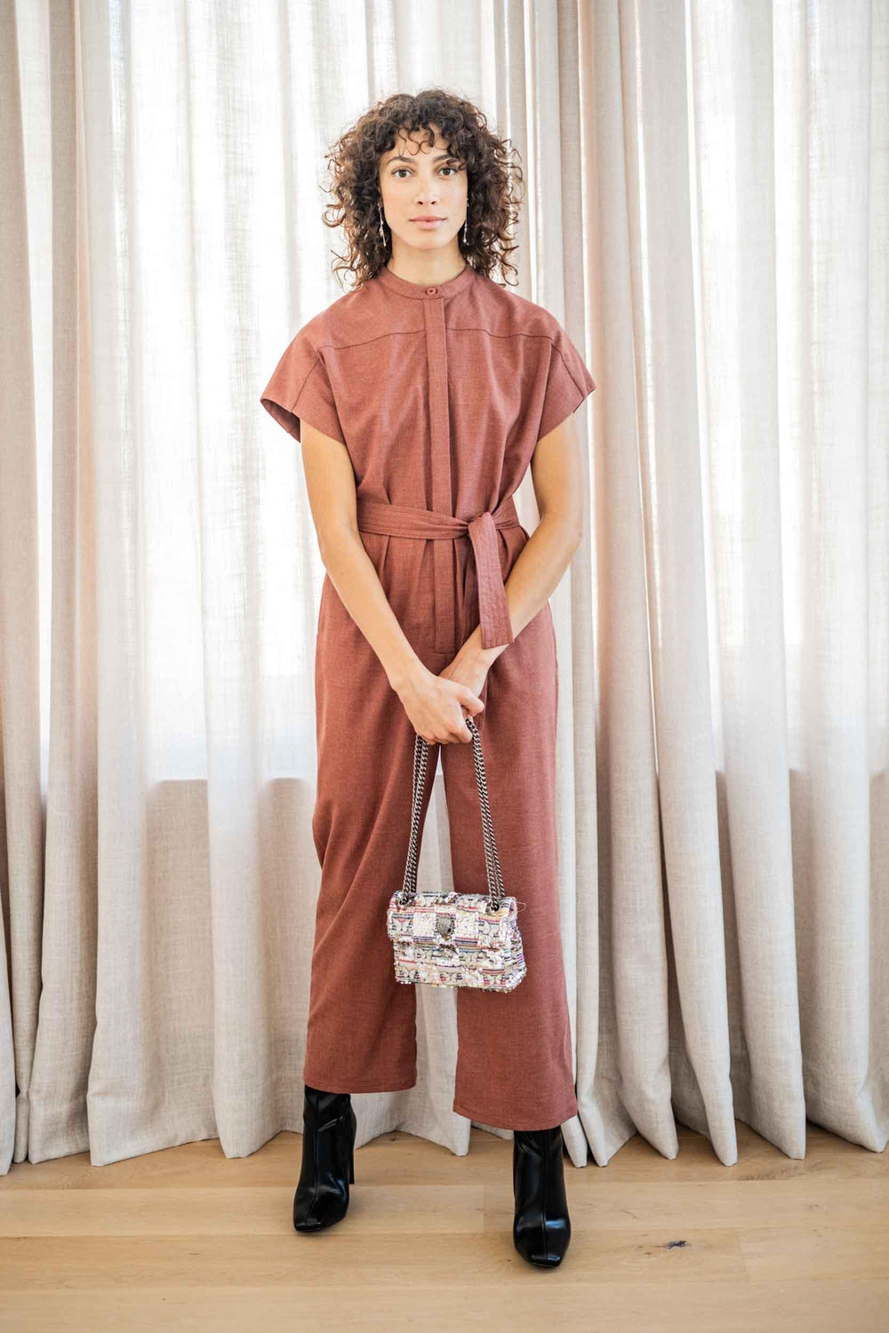 Woman wearing the Amelia Jumpsuit sewing pattern from Fibre Mood on The Fold Line. A jumpsuit pattern made in lyocell, poplin, corduroy, suede, flannel, twill, crepe, or linen fabrics, featuring a relaxed fit, short grown-on sleeves, standing collar, conc