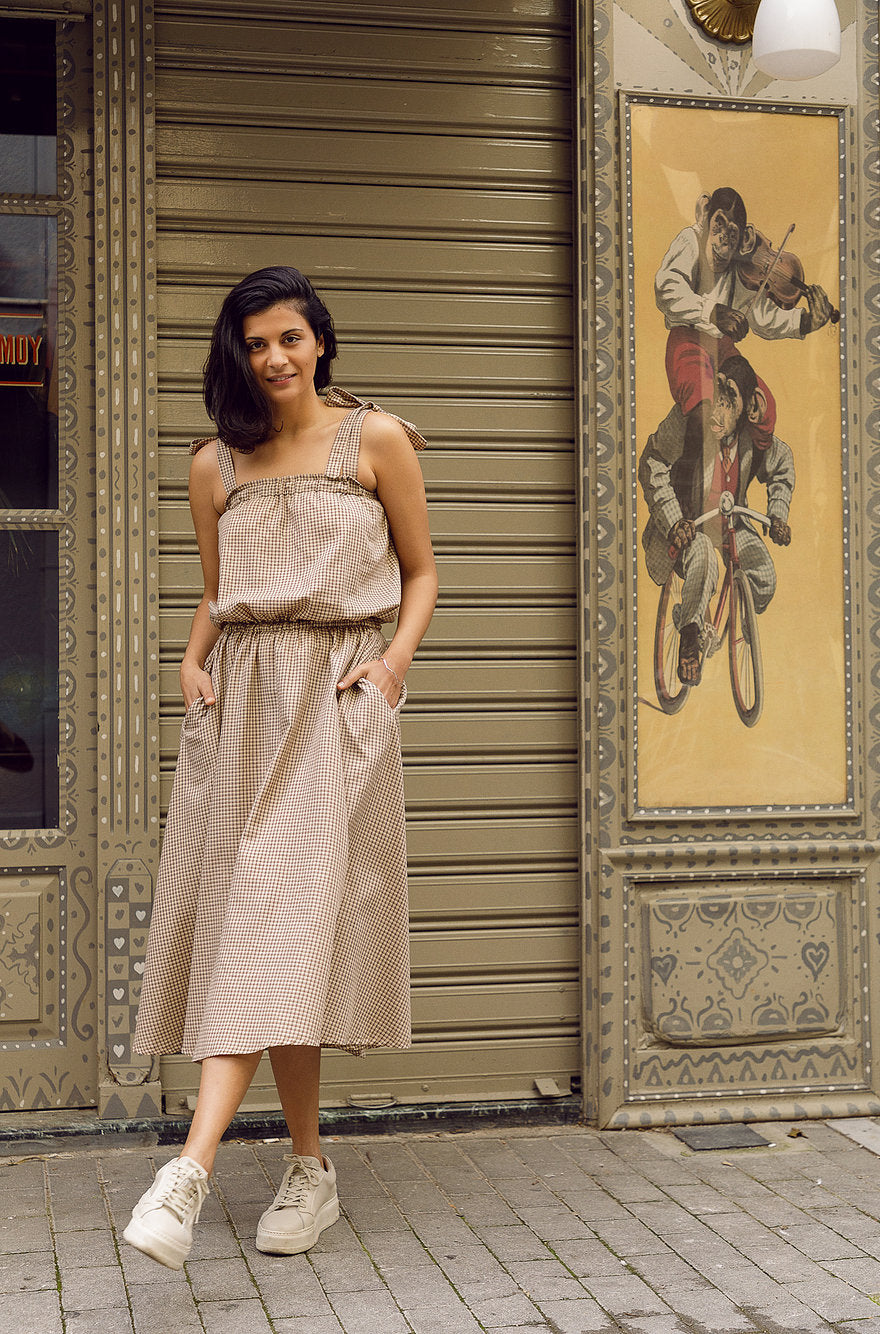 Woman wearing the Amelie Dress sewing pattern from The Patterns Room on The Fold Line. A dress pattern made in flowing woven or knit fabrics, featuring an elasticated chest and waist, relaxed fit, side seam pockets, no closures, tied shoulder straps and m