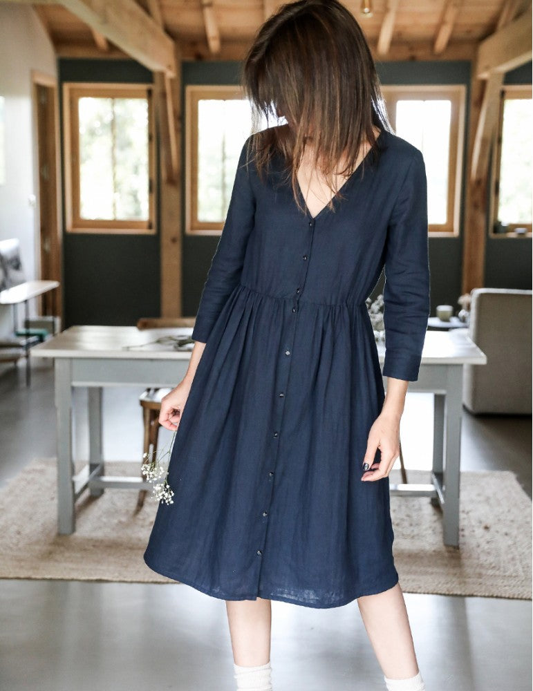 Woman wearing the Anaé Dress sewing pattern from Atelier Scämmit on The Fold Line. A dress pattern made in batiste, crepe, double gauze or light denim fabrics, featuring a button-front closure, 7/8 length sleeves with shaped cuffs, elasticated waist and v