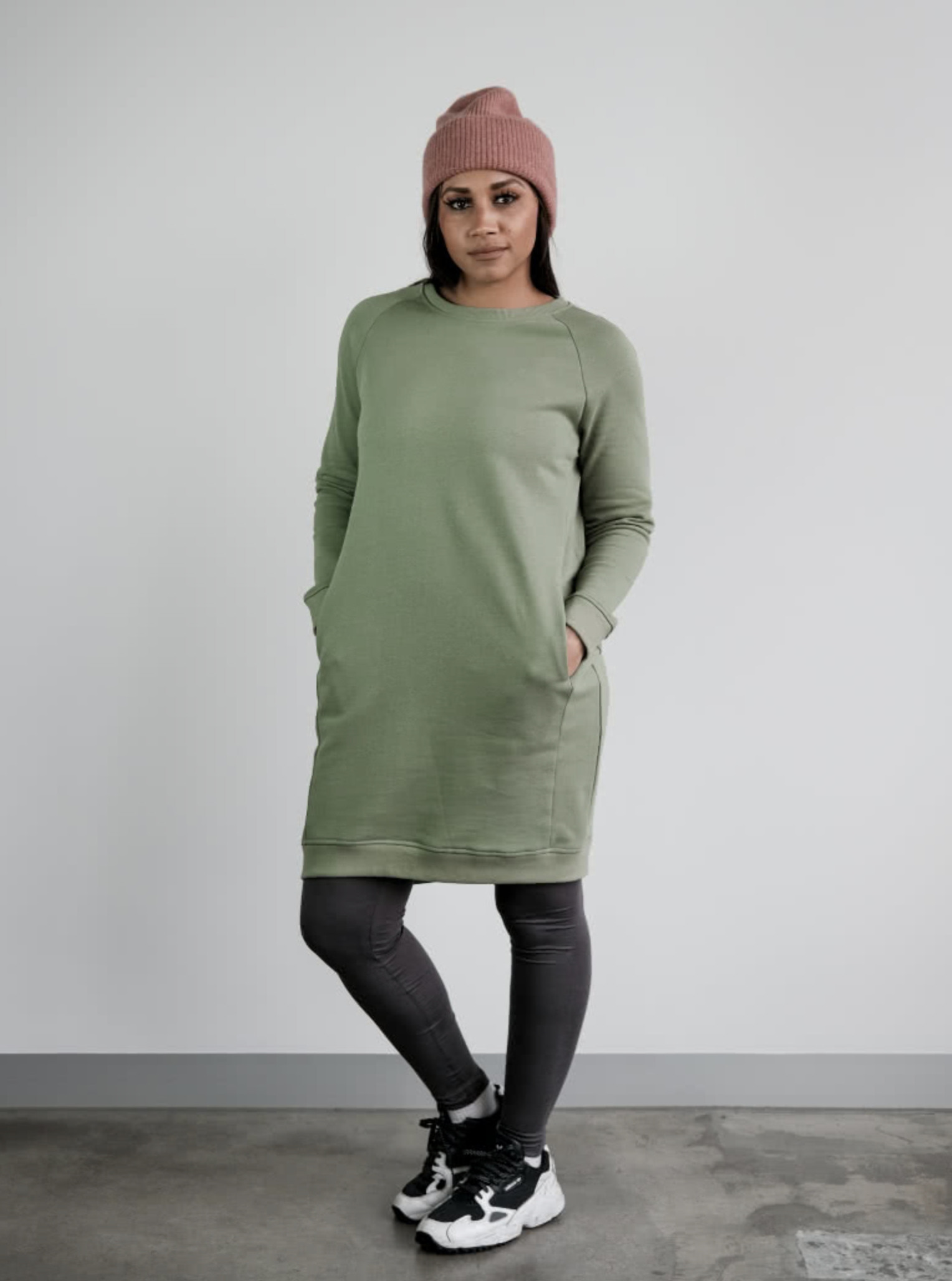 Woman wearing the Anderson Knit Dress sewing pattern from Style Arc on The Fold Line. A knit dress pattern made in French terry, fleece or rugby knit fabrics, featuring a crew neck, raglan sleeves, side front panels, in-seam pockets, slight high-low hemli