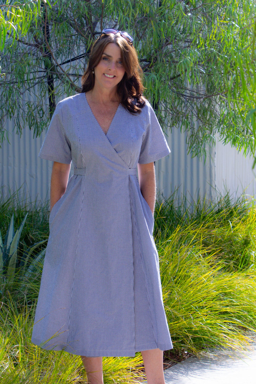 Woman wearing the Andrea Wrap Dress sewing pattern from Blue Dot Patterns on The Fold Line. A wrap dress pattern made in chambray, light to medium weight cottons, lightweight linen, poplin, lightweight denim, crepe or challis fabrics, featuring a loose fi
