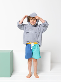 Child wearing the Children's Ash Anorak sewing pattern from Style Arc on The Fold Line. An Anorak pattern made in showerproof nylon fabric, cotton, or polyester fabrics, featuring a hip-length, unlined hood, raglan sleeves, elasticated cuffs, front neck t