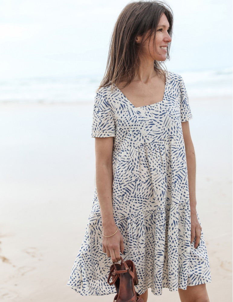 Woman wearing the Astree Dress sewing pattern from Atelier Scammit on The Fold Line. A dress pattern made in batiste, crêpe, double gauze or light denim fabrics, featuring a trapezium neckline at the front and a V at the back, short sleeves and above knee