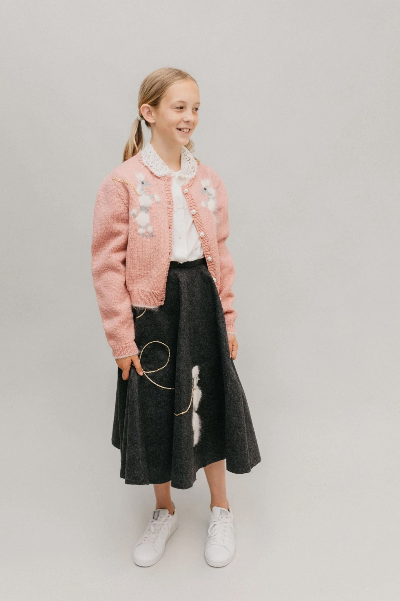 Girl wearing the 256 Child/Adult At the Hop Outfit sewing pattern from Folkwear on The Fold Line. A 1950s inspired pattern made in felt, cotton, wool, rayon, or gabardine fabric, featuring a circle skirt with poodle appliqué, short sleeve blouse with a Pe