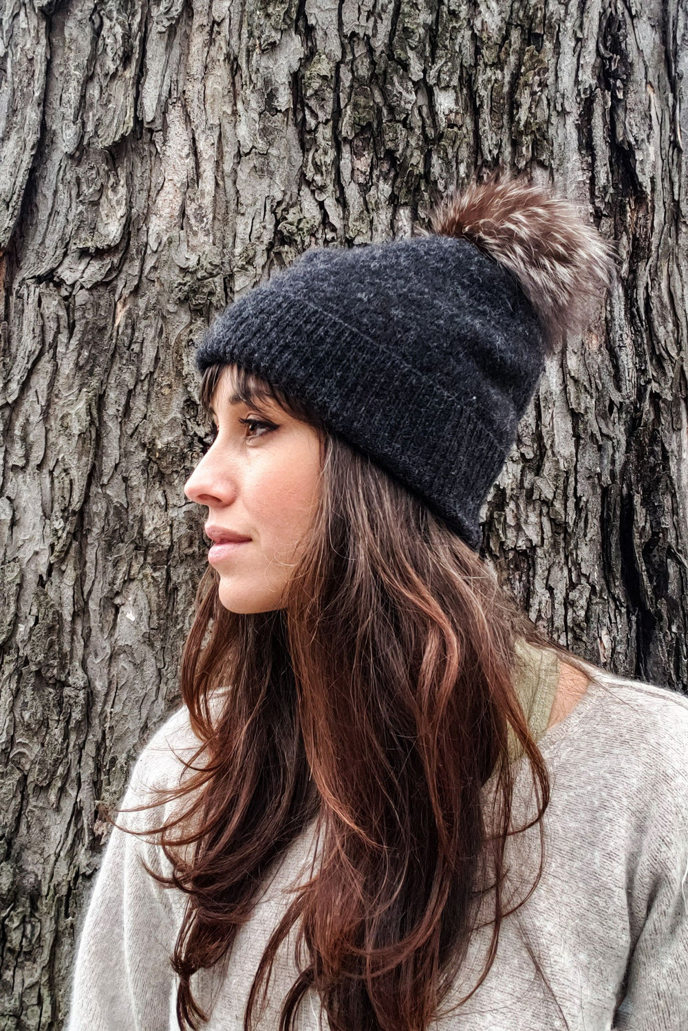 Woman wearing the Atlas Tuque Hat sewing pattern from Victory Patterns on The Fold Line. A beanie hat pattern made in recycled sweaters, cable knit or cardigan knit fabrics, featuring a turned back ribbed band, pom-pom, and relaxed fit.