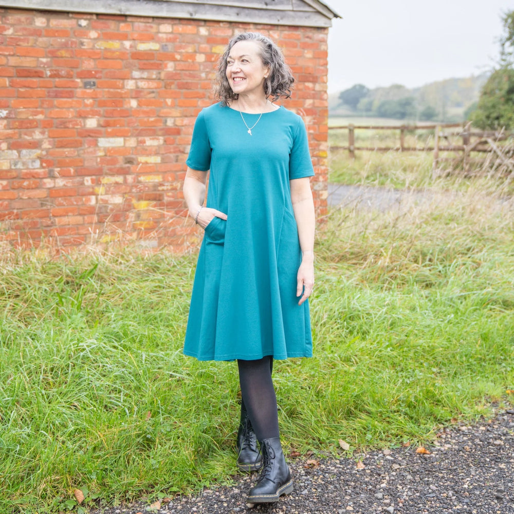 Woman wearing the Audrey Dress sewing pattern from Sew Me Something on The Fold Line. A flared swing dress pattern made in Jersey, lightweight knit, double-faced jersey, ponte roma, or interlock fabrics, featuring princess seams, short sleeves, in-seam po