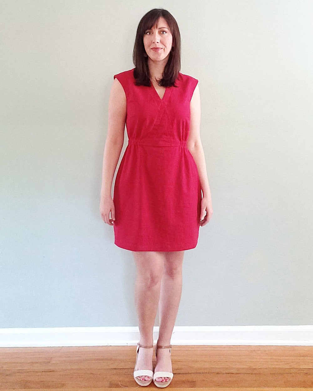 Woman wearing the Ava Dress sewing pattern by Pattern Scout. A sleeveless dress pattern made in linen, cotton sateen/lawn/batiste/chambray, rayon, lyocell or Tencel fabrics, featuring a faux wrap bodice, elasticated waist, above knee length finish and V-n