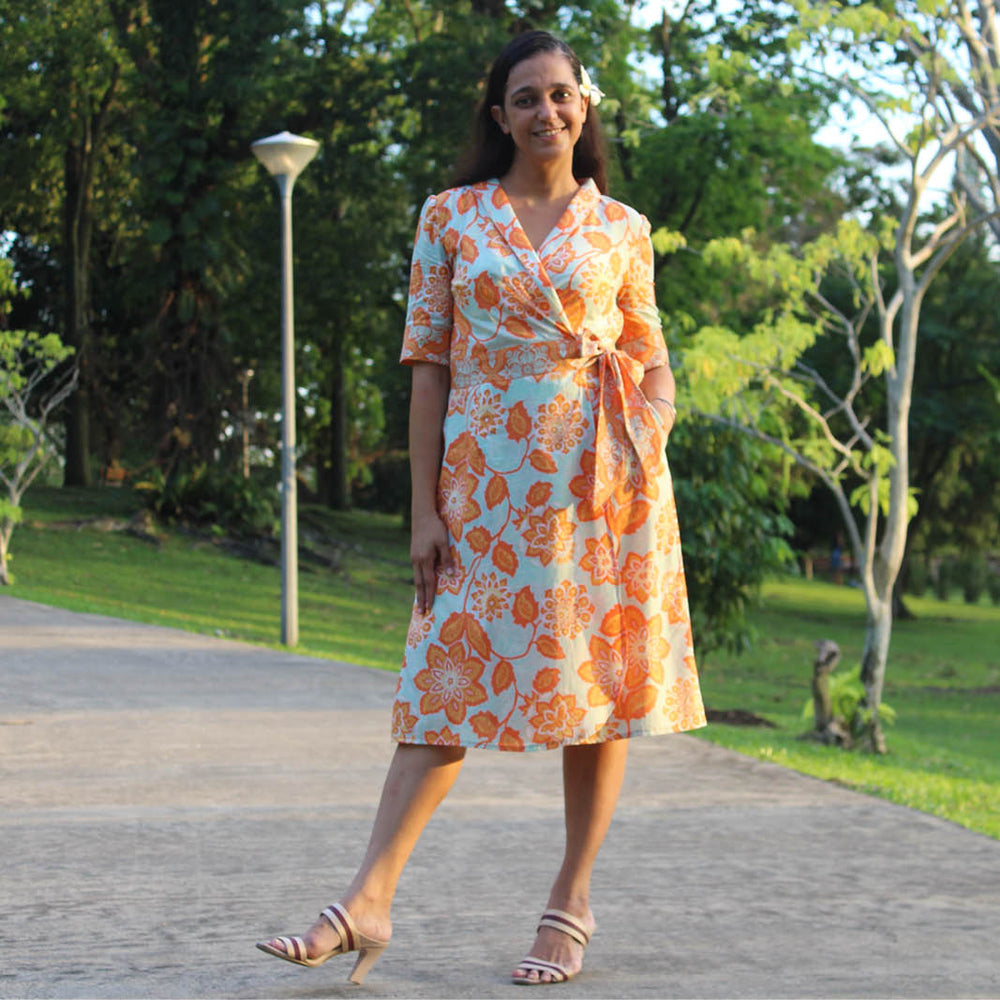 Woman wearing the Ava Wrap Dress sewing pattern from Wardrobe by Me on The Fold Line. A wrap dress pattern made in cotton, silk, modal, viscose or linen fabrics, featuring bust darts, elbow-length cuffed sleeves, side pockets, slightly curved hemline, bac