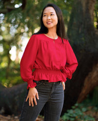 Woman wearing the Azores Top sewing pattern from Itch to Stitch on The Fold Line. A blouse pattern made in crepe, challis, silk, satin, georgette or charmeuse fabrics, featuring a voluminous fit, shirred waist and wrists, slit at the centre front neckline