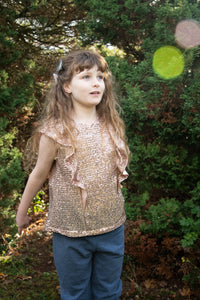 Child wearing the Baby/Child/Teen Alice Top sewing pattern by Bobbins and Buttons. A sleeveless, top pattern made in cottons, double gauze or linen fabrics, featuring a deep ruffle that runs over the shoulder and keyhole back opening.