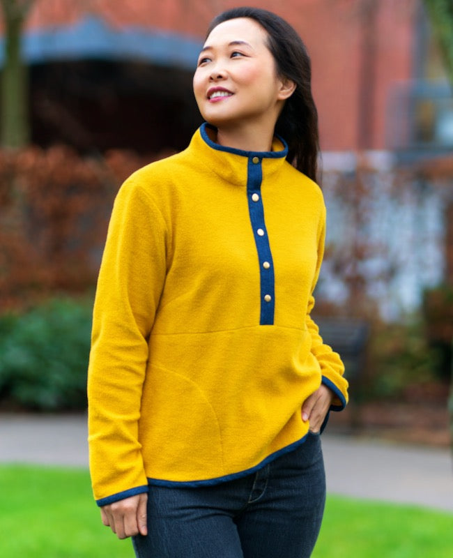 Woman wearing the Bainbridge Pullover sewing pattern from Itch to Stitch on The Fold Line. A pullover pattern made in microfleece, sherpa fleece or sweatshirting fabrics, featuring a half-snapped front placket, stand-up collar, long sleeves, bias-bound he