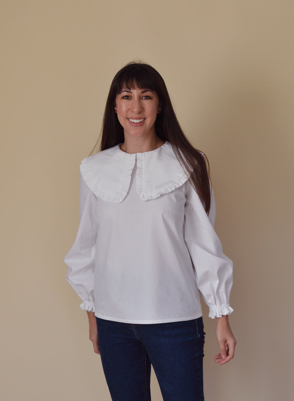Woman wearing the Bakerloo Blouse sewing pattern from Nina Lee on The Fold Line. A blouse pattern made in lawn, poplin, chambray, silk dupion, crepe or fine needlecord fabrics, featuring a large ruffled collar, balloon sleeves with elasticated cuffs and r
