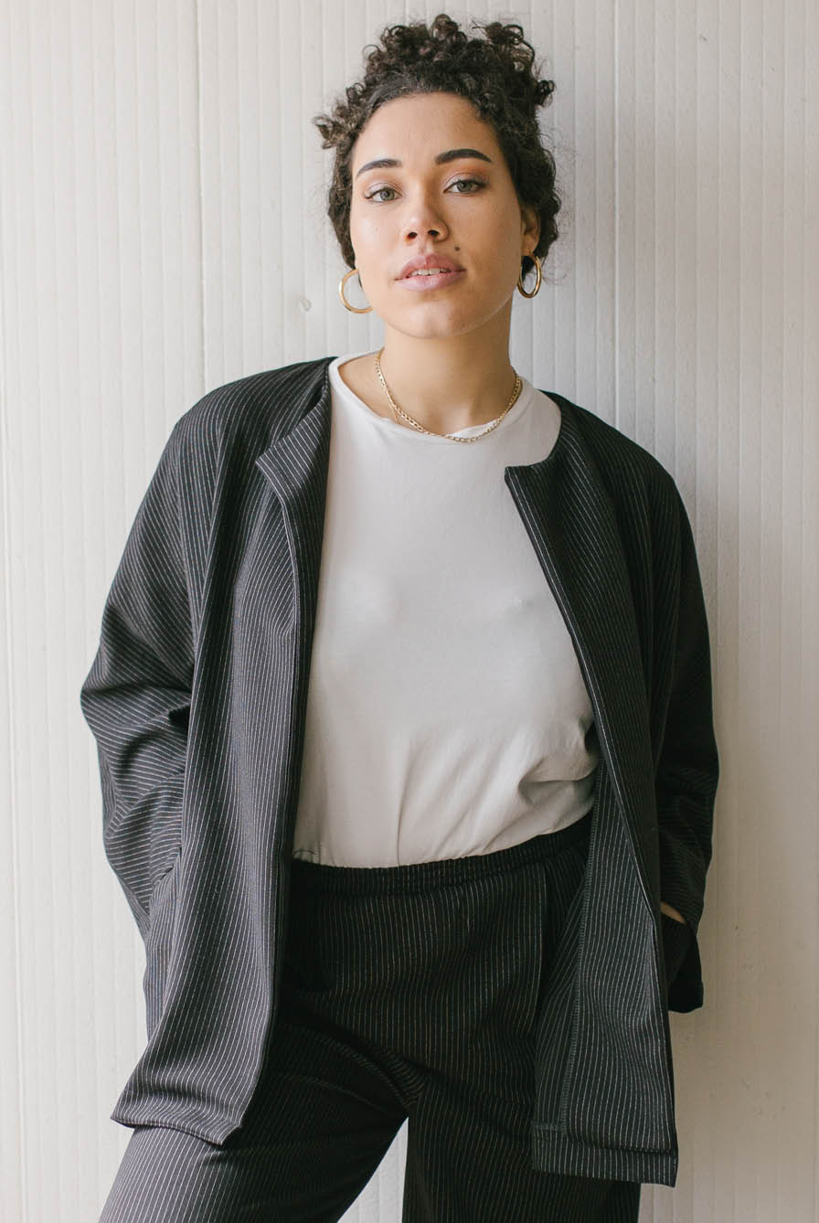 Woman wearing the Basic Jacket sewing pattern from JULIANA MARTEJEVS on The Fold Line. A jacket pattern made in wool fabrics, featuring a round neck, front patch pockets, full length sleeves, top of thigh length, relaxed fit, and optional snap button clos