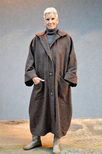 Woman wearing the Basics Overcoat sewing pattern from Folkwear on The Fold Line. A coat pattern made in cotton twill, heavy-weight linen, wool, sturdy knit, denim or canvas fabrics, featuring a roomy fit, low-calf length, dolman-like built-on sleeves, one