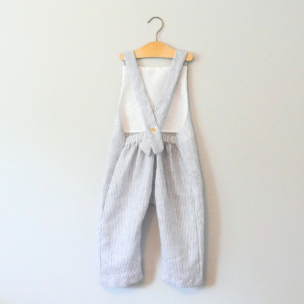 Child wearing the Baby/Child Beatnik Overalls sewing pattern from Elemeno Patterns on The Fold Line. A sleeveless overall pattern made in cotton knit or woven fabrics, featuring a relaxed fit, full length legs, elastic waistband on the back and one button