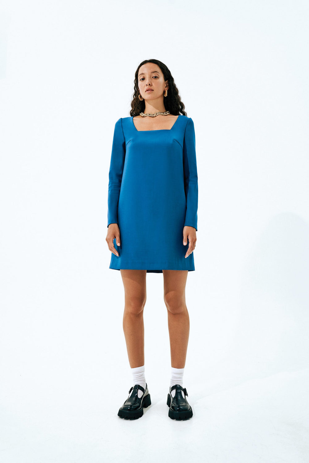 Woman wearing the Becky Dress sewing pattern from Vikisews on The Fold Line. A dress pattern made in dress-weight suiting, dress-weight wool, wool crepe or gabardine fabrics, featuring a semi-fitted trapeze style, free-hanging lining, deep square neckline