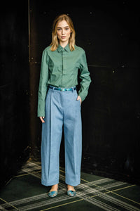 Woman wearing the Bernie Trousers sewing pattern from Fibre Mood on The Fold Line. A trouser pattern made in denim, linen, fine corduroy, gabardine or leather fabrics, featuring an ankle-length, front pleats, waistband, belt loops, welt pockets and fly zi