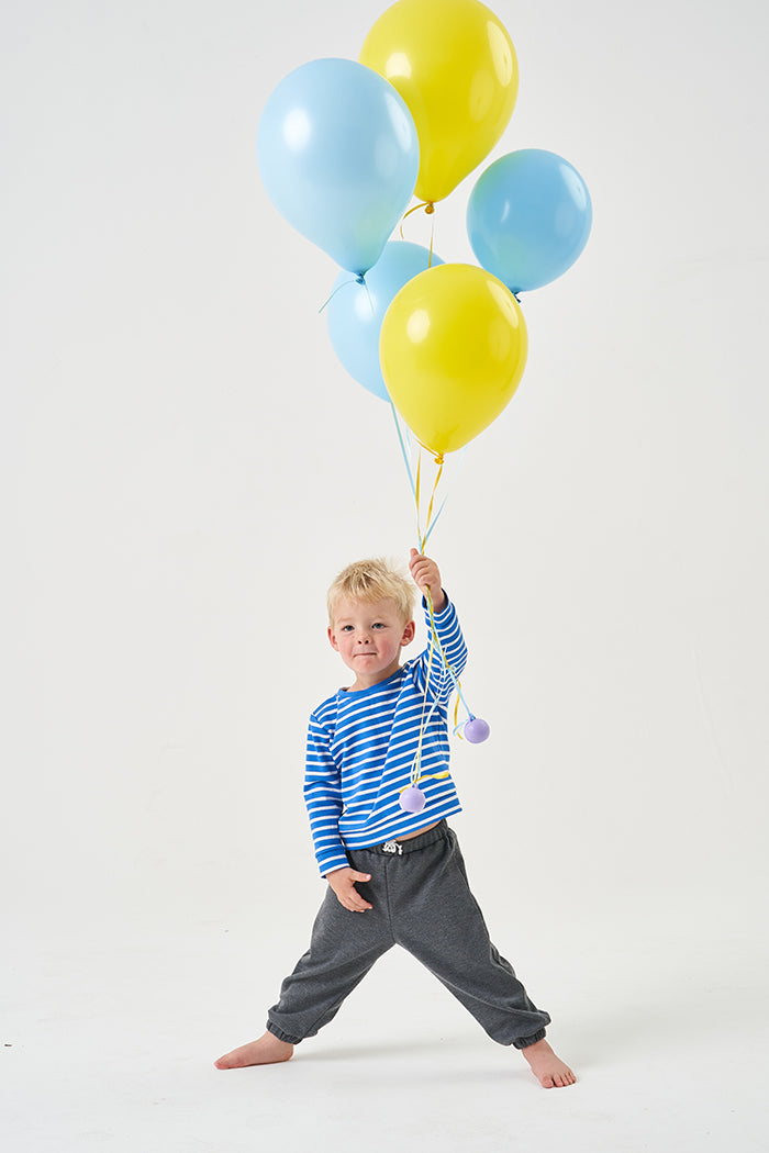 Child wearing the Baby/Child Birch Trousers sewing pattern from Poppy & Jazz on The Fold Line. A trouser pattern made in cotton jersey, lightweight ponte di roma, french terry or sweatshirt knits fabrics, featuring an elasticated waistband and cuffs, draw