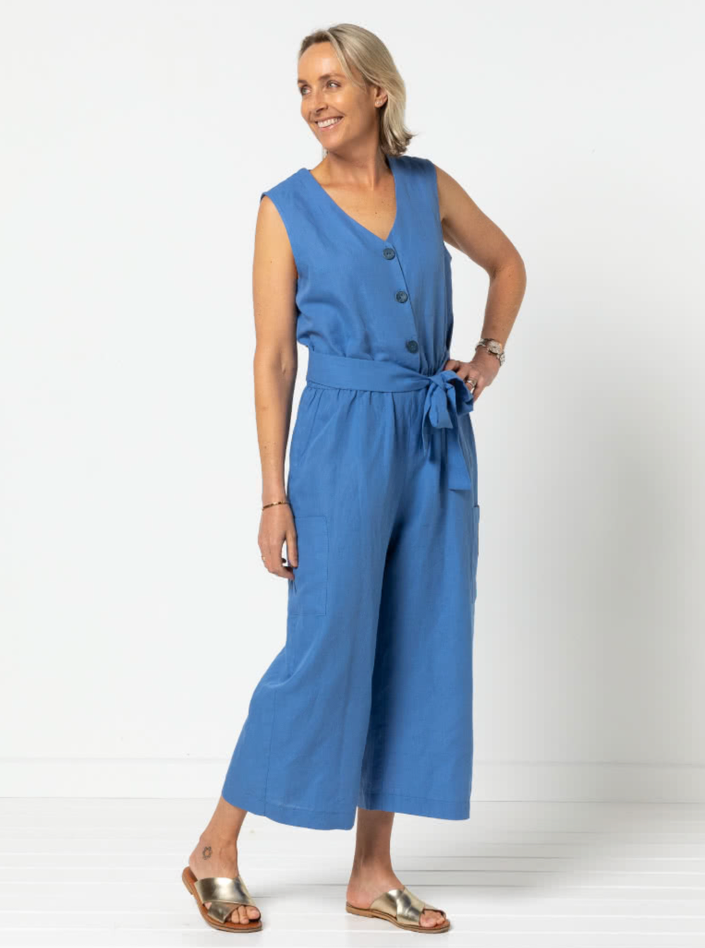 Woman wearing the Birdie Jumpsuit sewing pattern from Style Arc on The Fold Line. A jumpsuit pattern made in crepe, washed linen, or light ponte knit fabric, featuring a sleeveless bodice with buttons, armhole darts, v-neck, elastic waist, wide 7/8 length