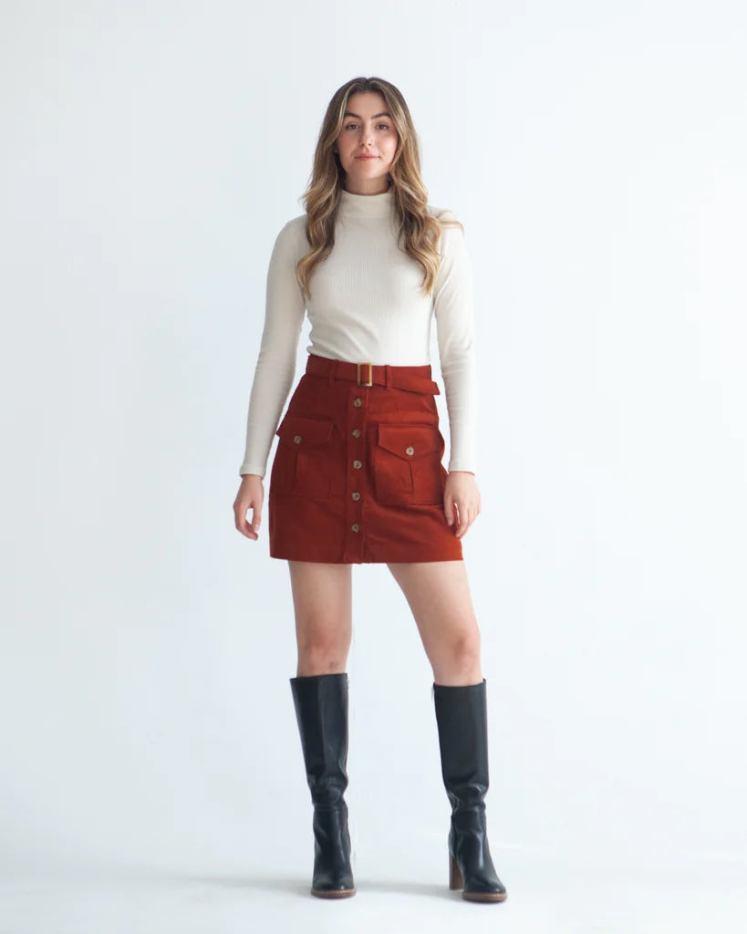 Woman wearing the Blair Skirt sewing pattern from True Bias on The Fold Line. A skirt pattern made in denim, corduroy, linen and wool fabrics, featuring a fitted silhouette, mini length, button-front opening, belt loops, belt, and pockets with inverted pl