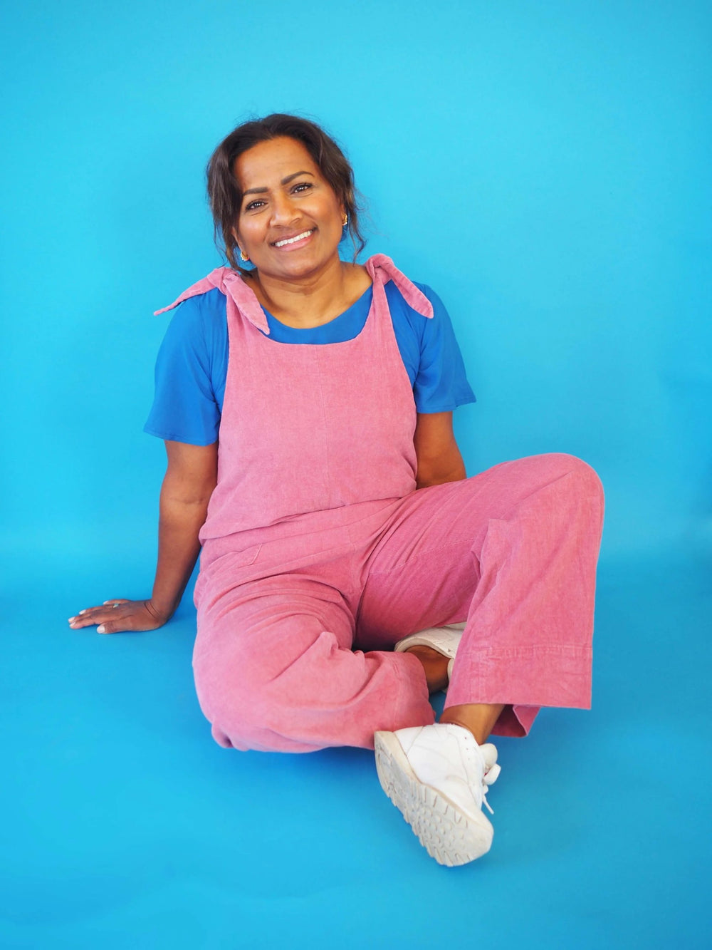 Woman wearing the Britt Dungarees sewing pattern from Melilot on The Fold Line. A dungaree pattern made in woven or jersey fabrics, featuring shoulder straps with bow-tie fastenings, side seam pockets, and a relaxed fit.