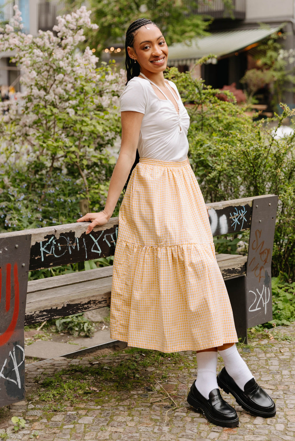 Woman wearing the Abbie Skirt sewing pattern from JULIANA MARTEJEVS on The Fold Line. A skirt pattern made in cotton poplin fabric, featuring an elasticated waist, side pockets, gathered tier, and midi length.