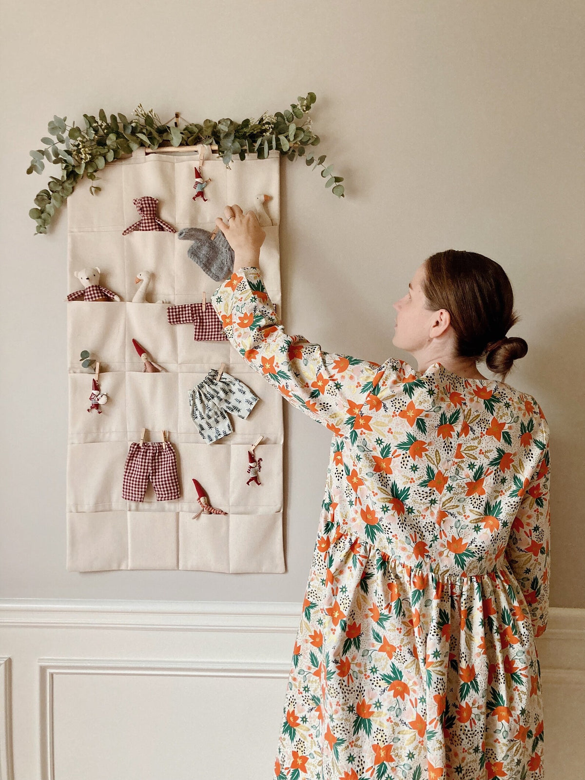 Woman using the Adam Organizer sewing pattern from Me & Kiddo Patterns on The Fold Line. A hanging organizer or advent calendar pattern made in cotton, cotton canvas, or linen fabric, featuring 24 pockets.