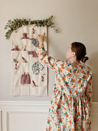Woman using the Adam Organizer sewing pattern from Me & Kiddo Patterns on The Fold Line. A hanging organizer or advent calendar pattern made in cotton, cotton canvas, or linen fabric, featuring 24 pockets.