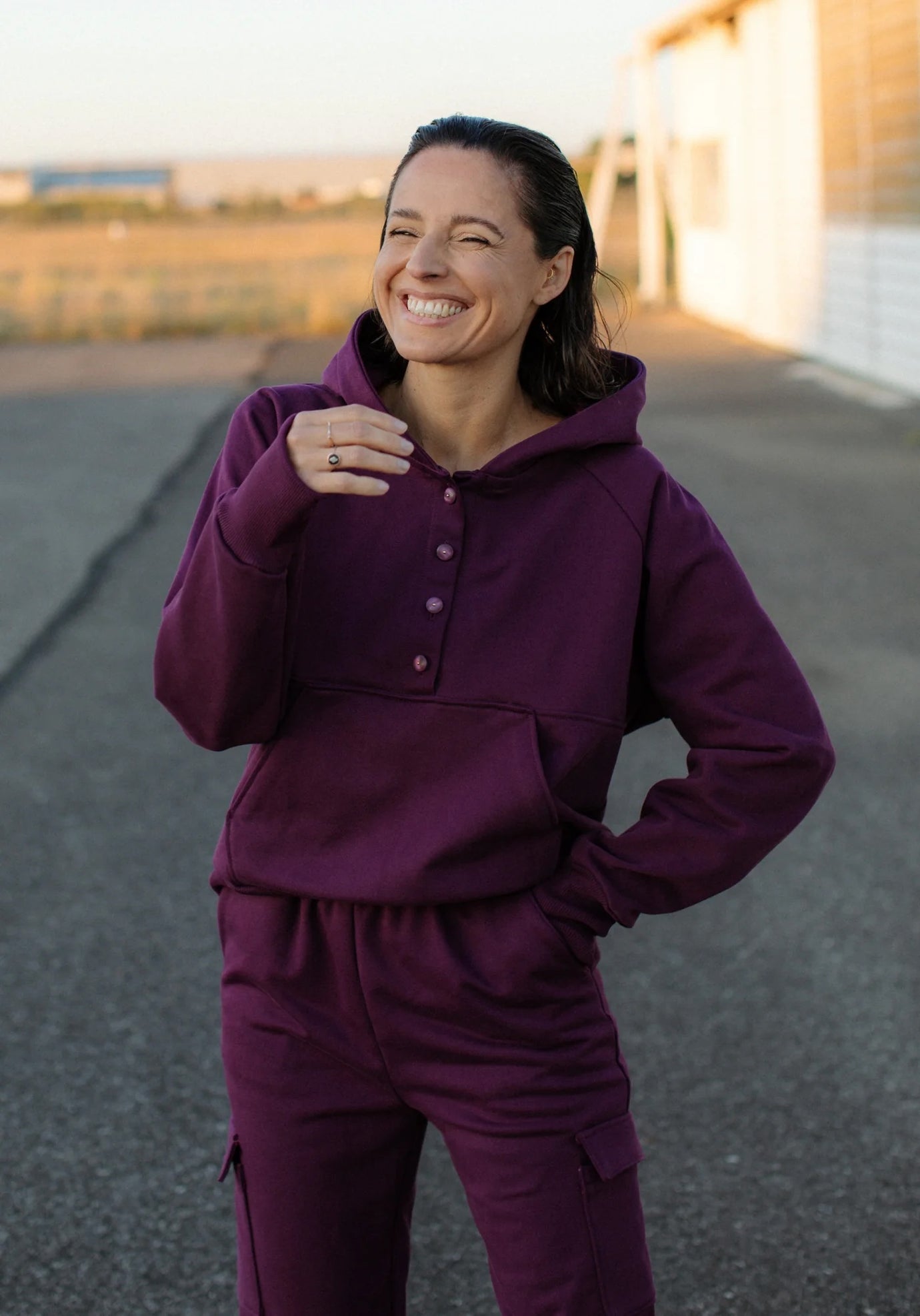 Woman wearing the Adèle Sweatshirt sewing pattern from Maison Fauve on The Fold Line. A top pattern made in jersey, French terry, or sweater knit fabric, featuring a hood, button placket, kangaroo pocket, long raglan sleeves, and cuffs with thumb openings.