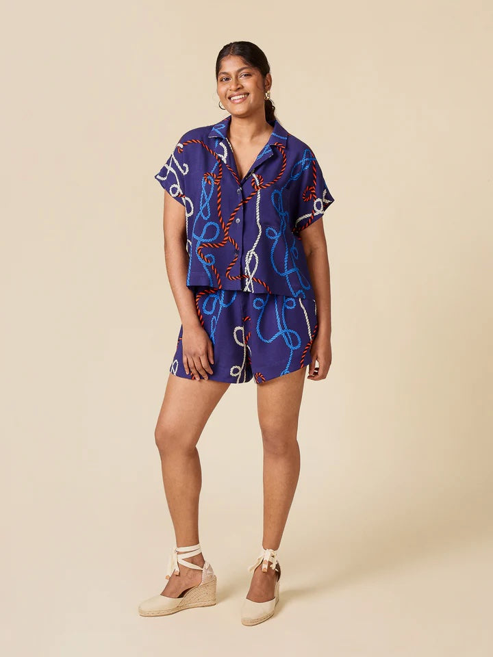 Woman wearing the Adriana Matching Set sewing pattern from Closet Core Patterns on The Fold Line. A top and shorts pattern made in cotton poplin, linen, double gauze, seersucker, chambray, oxford, broadcloth, viscose, tencel, silk, or voile fabric, featuring a shirt with a camp collar, button front, and short grown-on sleeves, and shorts with a high rise, elastic waistband, and pockets.