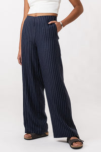 Woman wearing the Airi Wide Leg Trousers sewing pattern from Named on The Fold Line. A trousers pattern made in medium weight non-stretch trousering fabric, featuring a high waist, side pockets, back patch pockets, invisible zipper, and wide legs.