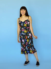 Woman wearing the Alameda Slip Dress sewing pattern from Nina Lee on The Fold Line. A strappy dress pattern made in crepe, viscose, silk, or linen fabric, featuring a slinky bias cut, draped neckline, nipped-in waist seam, and below-the-knee length.