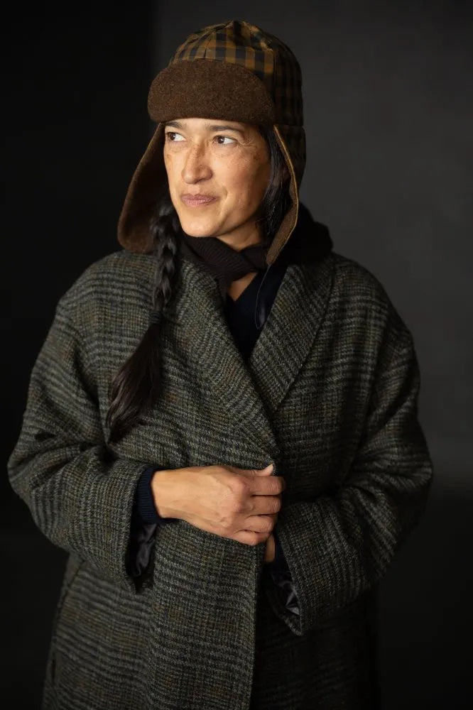 Woman wearing the Alberta Hat sewing pattern from Merchant & Mills on The Fold Line. A trapper hat pattern made in oilskin, dry oilskin, mid weight cotton canvas or drill, corduroy, mid-heavy weight denim, or wool coating fabric, featuring a lining and ear flaps.