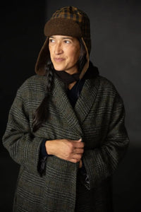 Woman wearing the Alberta Hat sewing pattern from Merchant & Mills on The Fold Line. A trapper hat pattern made in oilskin, dry oilskin, mid weight cotton canvas or drill, corduroy, mid-heavy weight denim, or wool coating fabric, featuring a lining and ear flaps.