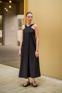 Woman wearing the Alberthe Dress sewing pattern from Fibre Mood on The Fold Line. A sleeveless dress pattern made in poplin, cotton twill, polycotton, denim, linen, double gauze, seersucker, chambray, lyocell, or crepe fabric, featuring a crossed neckline at the front, concealed zipper in the side seam, and midi length.