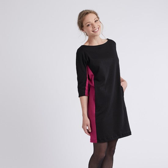 Woman wearing the Amazone Dress sewing pattern from Coralie Bijasson on The Fold Line. A dress pattern made in crepe, fleece, or milano fabric, featuring a bateau neckline, side panels, 3/4 length grown-on sleeves, and a mini length.