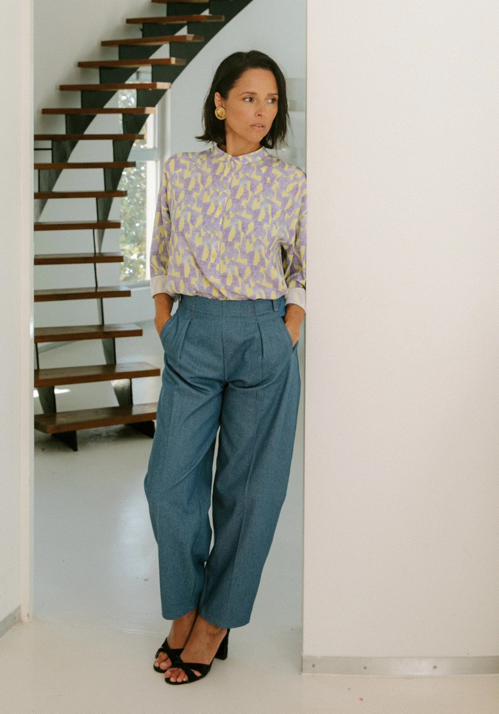 Woman wearing the Andrea Trousers sewing pattern from Maison Fauve on The Fold Line. A trousers pattern made in cotton gabardine, denim, dupion, a soft jacquard, mid weight velvet, or suiting wool fabric, featuring a barrel leg, front pleats, welt pockets at the front, and patch pockets at the back.